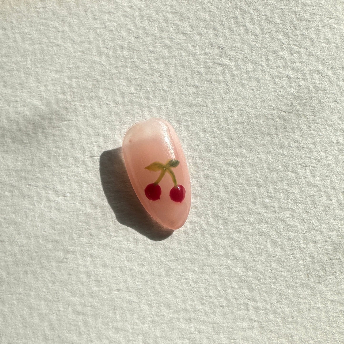 Small pink cherry with a face on a white paper towel