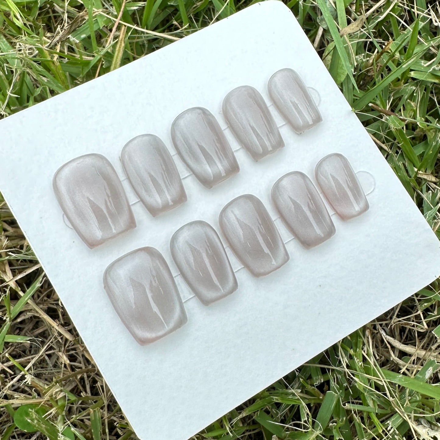 handmade Set of gray full moon cat eyes press nail on a white tray in grass