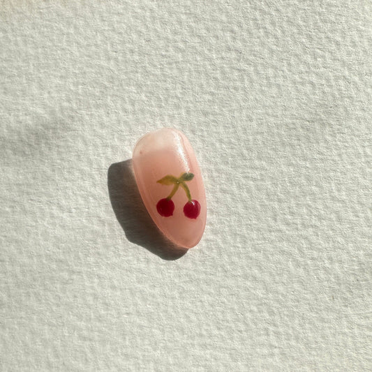 Small pink cherry with a face on a white paper towel