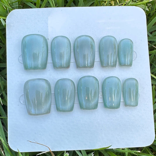 Set of light blue full moon  cat eyes press on nail on a white tray with grass in the background