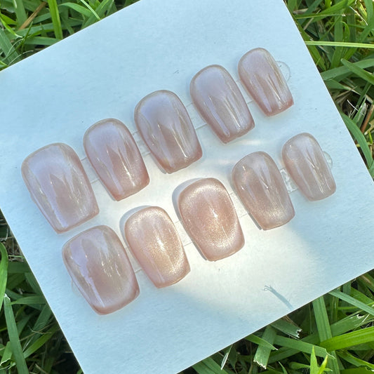 Set of press-on nails on a white card on grass in nude full moon color 